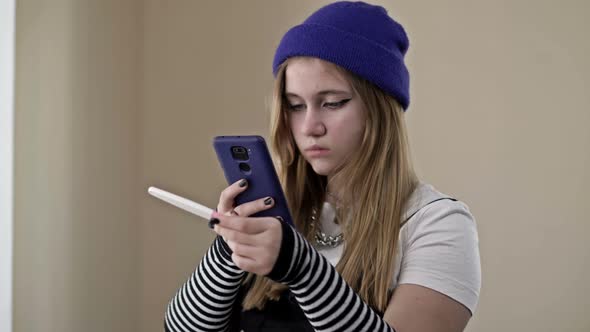 Frightened and Upset Teenage Girl Takes a Picture of a Pregnancy Stick Test on a Mobile Phone alt