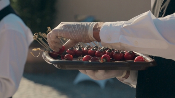 Waiter Takes Stuffed Cherry Tomatoes From The Tray alt