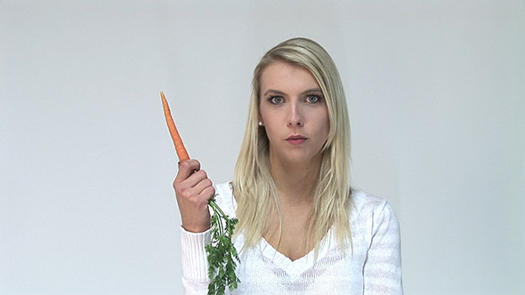 Happy Young Woman Eating A Carrot