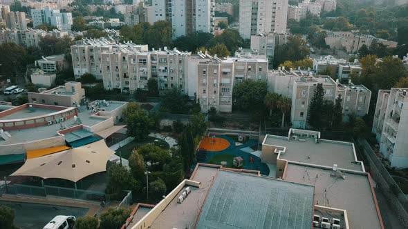 Aerial Tracking Past Sunlit Houses on Hilltop at Sunrise in Haifa Israel alt