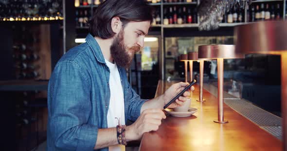 Male Browsing Smartphone in Bar