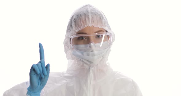 Portrait of Woman in a Protective Suit Mask Gloves and Glasses Wagging Her Finger