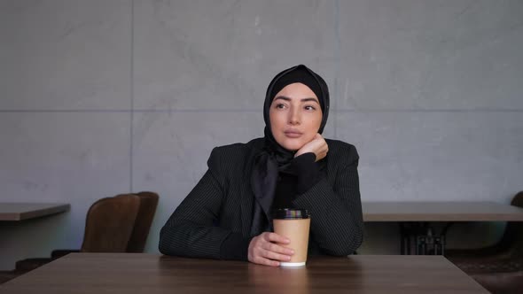 Sad Alone Young Muslim Business Woman in Hijab Drinking Coffee in Cafe and Thinking About Problem