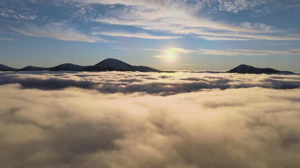 Aerial View of Vibrant Sunrise Over White Dense Fog with Distant Dark Peaks of Carpathian Mountains alt
