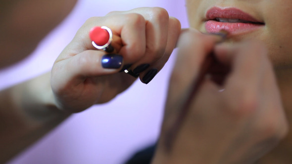 Make-up Artist Applying Lipstick To A Woman Lips 