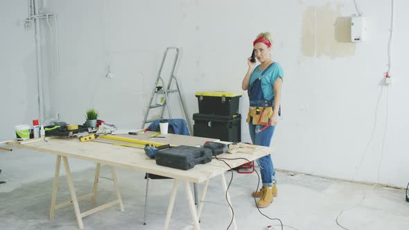 Cheerful Female Carpenter Talking on Smartphone alt
