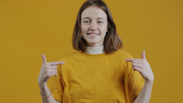 Slow Motion Portrait of Young Woman with High Self Esteem Pointing at Herself and Smiling alt