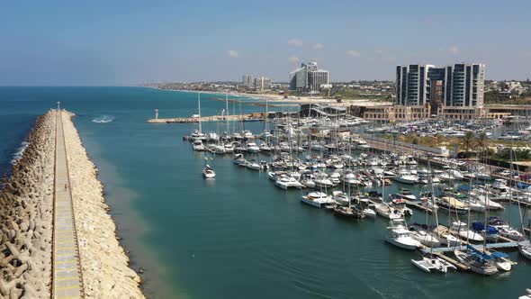 Speedboat enters Herzliya marina as a sailboat departs where several luxury ships are moored to the alt