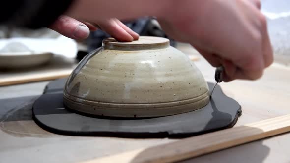Clay being trimmed in a circle with knife using a bowl as guide by hand on a ceramics workshop, Hand alt