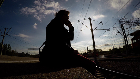 Silhouette of Man Sitting On Edge Of Platform