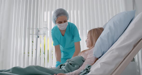 Nurse Medicating Sick Child Lying in Bed and Getting Drip in Hospital Room alt