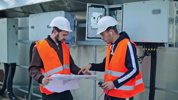 Engineers discuss the further work with a paper plan alt