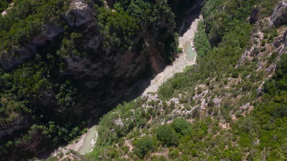 Aerial top down over deep gorge of Benje Canyon between huge green mountains. alt