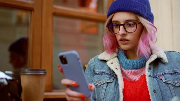 Serious woman in hat looking at phone in cafe alt