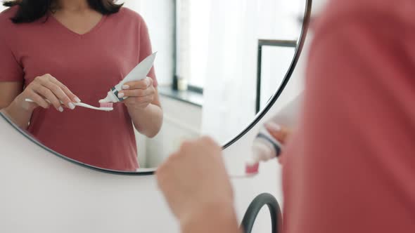 Close-up of Woman's Hand Squeezing Toothpaste on Brush in Bathroom Ready To Clean Her Teeth alt