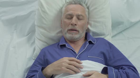 Senior man loudly snoring and puffing in bed, sleeping problems at old age alt