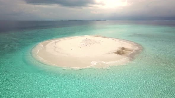 Aerial view of a small tropical island with white sand beach and turquoise sea water.	 alt