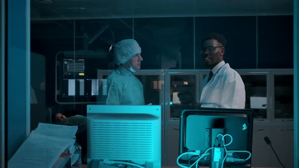 Darkskinned and Adult Caucasian Doctors Discuss Patient Treatment Plan alt