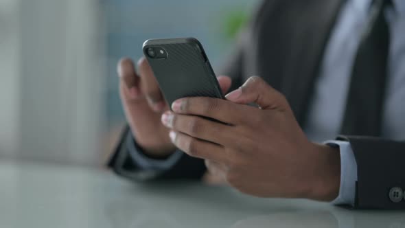 Close up of Hands of African Businessman using Smartphone alt