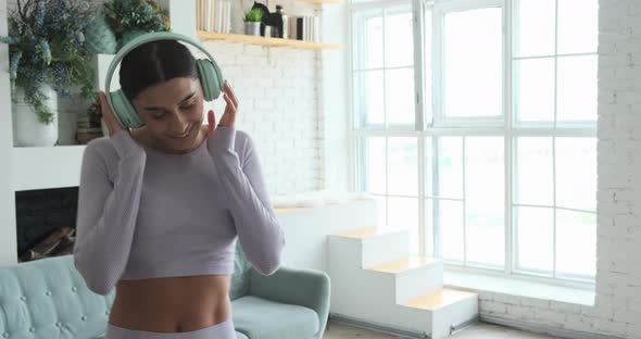 Happy Cheerful Young Woman Dancing Alone at Home and Using Smartphone for Listening Music alt