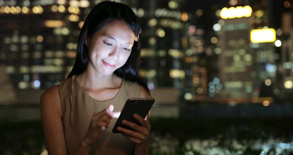 Woman using smart phone in Hong Kong at night  alt
