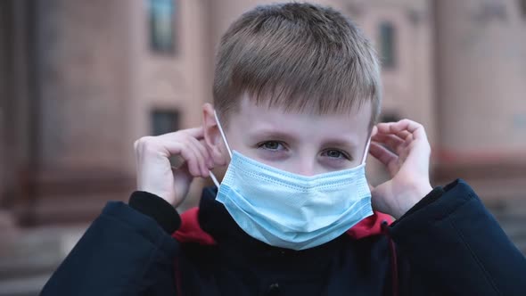 Child Boy Putting on Medical Mask for Coronavirus Prevention