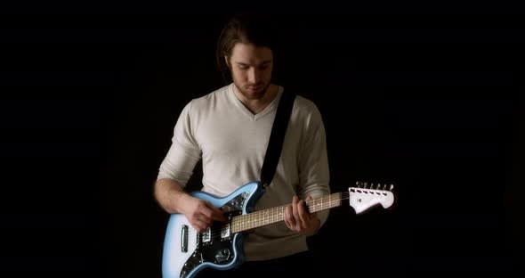 Creative Musician in a Gray Jumper on a Black Background Plays Electric Guitar