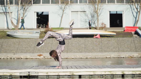 Young Athletic Female Gymnast Performs Handstand Pontoon Near Blue Lake alt