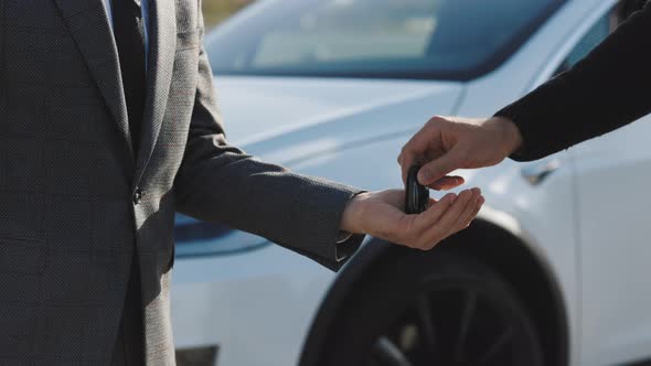 Male Hand Gives a Car Keys to Male Hand in the Car Dealership Close Up alt