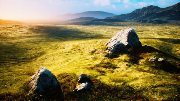 Meadow with Huge Stones Among the Grass on the Hillside at Sunset alt