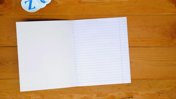 School teacher lays out a notebook in a line, colored pens and the alphabet for learning