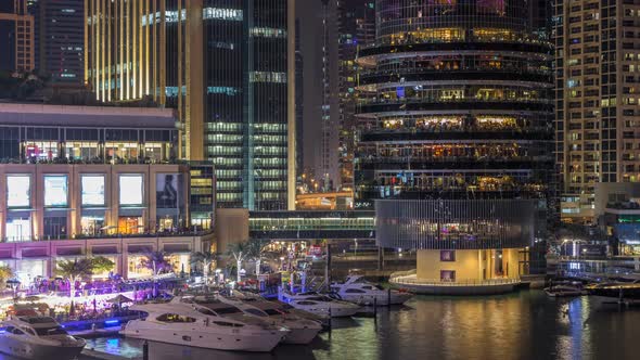 Aerial Vew of Dubai Marina with Shoping Mall Restaurants Towers and Yachts Night Timelapse United alt