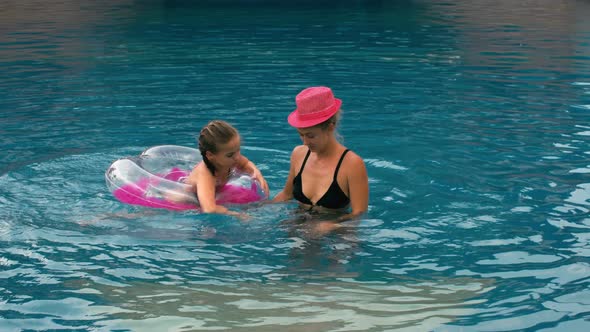 The Mother with Little Daughter Have Fun in the Pool alt
