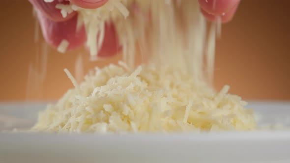 sprinkle grated parmesan cheese close-up. a man takes cheese in his hand and sprinkles it alt
