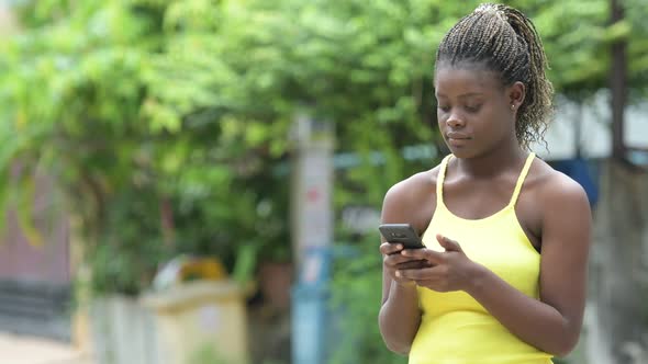 Young Happy African Woman Using Phone Outdoors alt