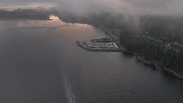 Aerial View of a small secluded town on the Pacific Ocean Coast during a cloudy summer sunrise. Take alt