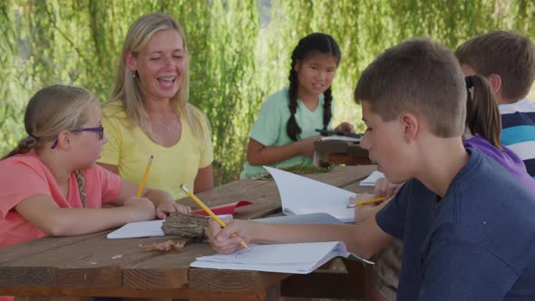 Kids at outdoor school writing in notebooks