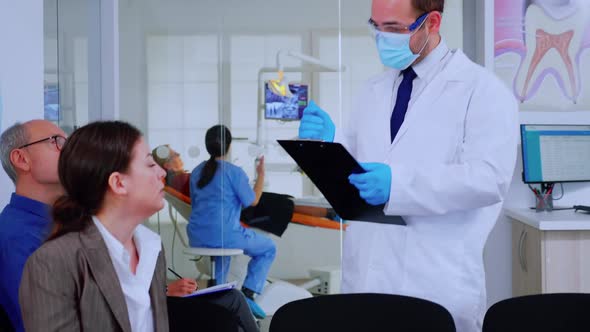 Doctor Taking Notes on Clipboard About Patient Dental Problems alt
