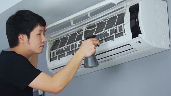 young man cleaning the air conditioner indoors at home