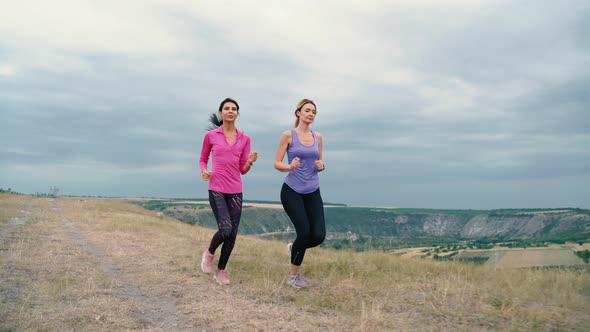 Two Young Women are Exercising with Outdoor Running When the Sun Sets in in Summer alt