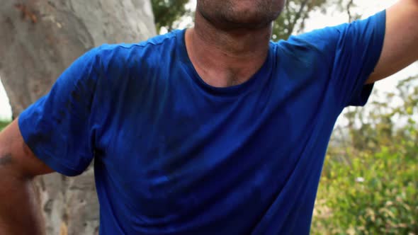 Portrait of fit man leaning on wooden pole during obstacle course alt