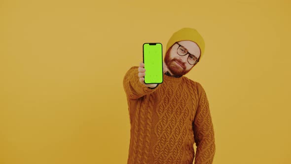 Young Man Showing the Smartphone Screen with Green Chroma Key and Showing the Thumb Up Gesture alt