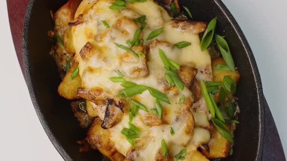 Fried Potatoes with Mushrooms and Cheese Spinning Round on Table