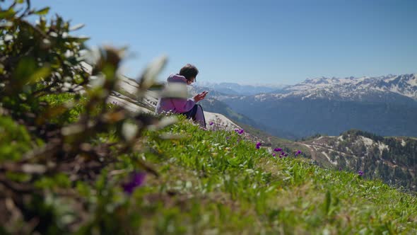 Girl Hiker Using Phone While Resting on Hillside with Great Overlook alt