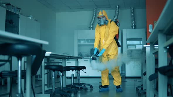 Person Sanitizes Laboratory Room with a Sprayer. alt