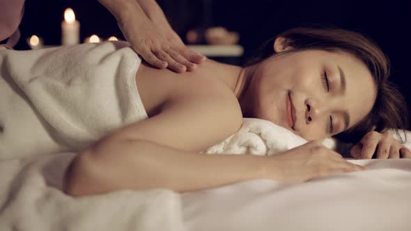 beautiful woman is relaxed by a dark oil massage in the spa