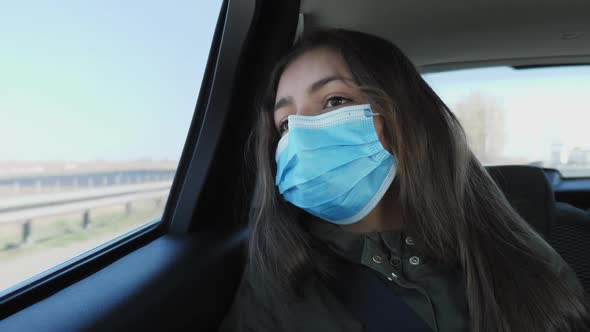 Girl in a Medical Mask Rides in a Car alt