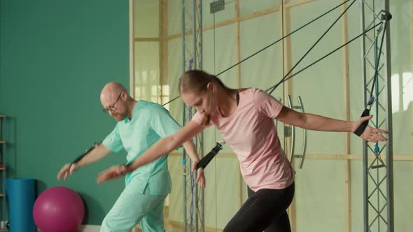 Sportswoman with a Personal Trainer Does Exercise with the Help of Expanders alt