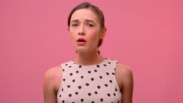 Young Millennial Woman Show Sympathy for the Interlocutor on a Pink Background. alt
