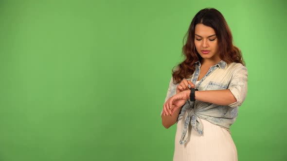 A Young Beautiful Caucasian Woman Works on a Smartwatch Then Smiles at the Camera  Green Screen